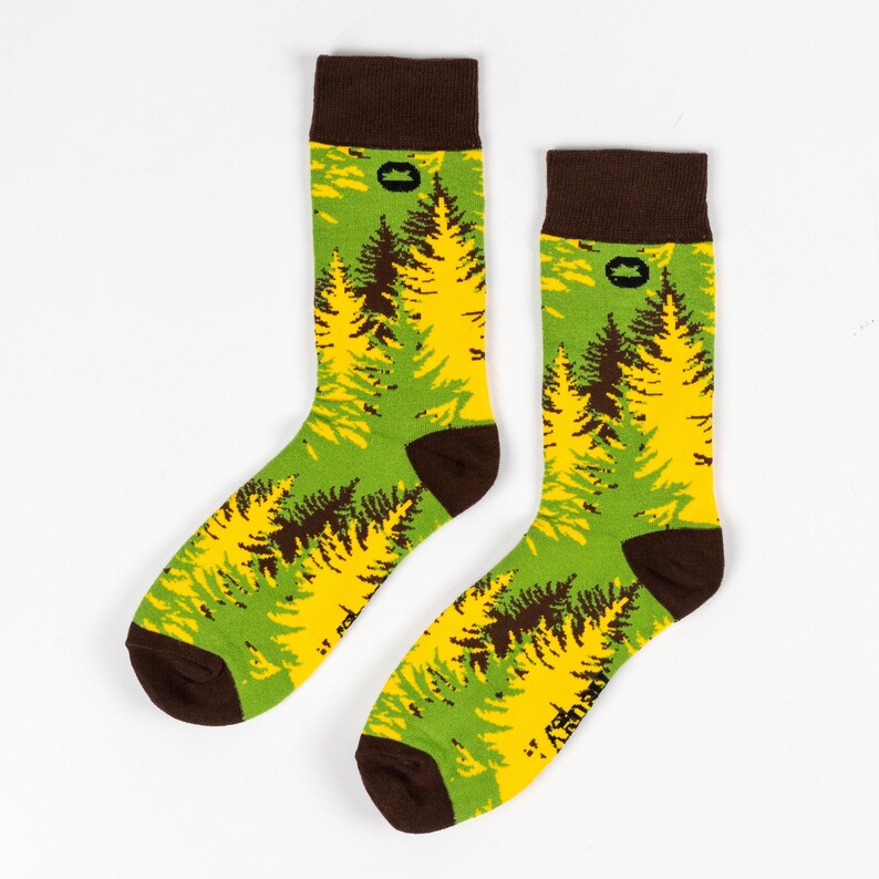 May include: A pair of green and yellow socks with a brown tree pattern. The socks have a brown cuff with a small brown logo.