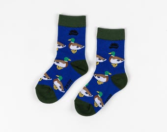 May include: A pair of blue socks with a green cuff and a pattern of brown and green ducks. The socks have the word "SMODS" printed on the bottom.
