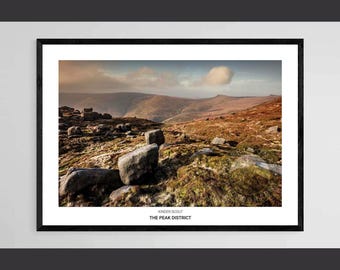 May include: A framed print of a landscape in the Peak District, featuring a view of Kinder Scout. The image shows a rocky, grassy landscape with distant hills under a cloudy sky. The text "Kinder Scout" and "The Peak District" are displayed.