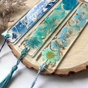 Pu&ograve; includere: Quattro segnalibri in resina blu e verde con fiori pressati e lettere dorate. I segnalibri hanno nappine. I segnalibri sono etichettati "Isabella", "Lea", "Eleanor Jane" e "Sophia".