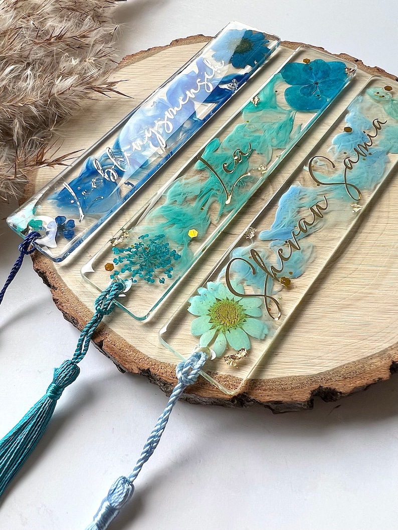 Pu&ograve; includere: Quattro segnalibri in resina blu e verde con fiori pressati e lettere dorate. I segnalibri hanno nappine. I segnalibri sono etichettati "Isabella", "Lea", "Eleanor Jane" e "Sophia".