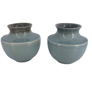 May include: Two blue ceramic vases with a brown glaze on the top edge. The vases are round and have a smooth, glossy finish.