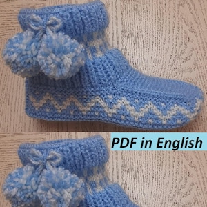 Puede incluir: Botas de pantuflas de punto azul claro con patrones de zigzag blancos y pompones. Las botas tienen un puño doblado y un lazo. El texto "PDF in English" es visible. Estas acogedoras botas de pantuflas son ideales para uso en interiores.
