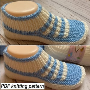 Puede incluir: Una zapatilla de punto en tonos blanco y azul claro, exhibida en una horma de pie. La zapatilla presenta un diseño acanalado con ribete y puntera azules. El texto "PDF knitting pattern" es visible en la parte inferior.