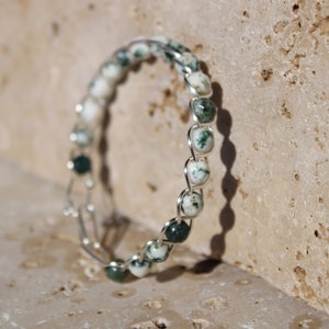 May include: A silver wire wrapped bracelet with green and white agate beads.