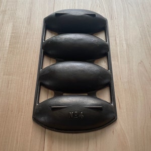 May include: Black cast iron bread pan with three oval-shaped molds. The pan is labeled "No. 4".