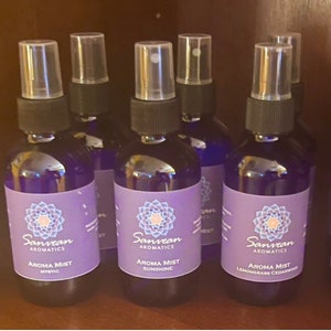 May include: Five small blue glass bottles with black spray tops and purple labels. The labels feature a floral design and the text "Sanvean Aromatics Aroma Mist" with different scents: Mystic, Sunshine, Lemongrass Cedarwood.