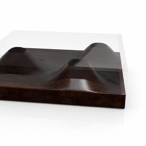 May include: A modern coffee table with a dark brown, textured wooden base featuring three raised, organic shapes. A clear, rectangular glass top sits above the base. The table is designed with a minimalist aesthetic.