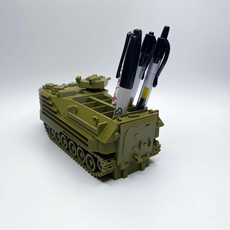 May include: A green toy military vehicle with a pen holder in the back. The vehicle has a track system and a small turret on top.