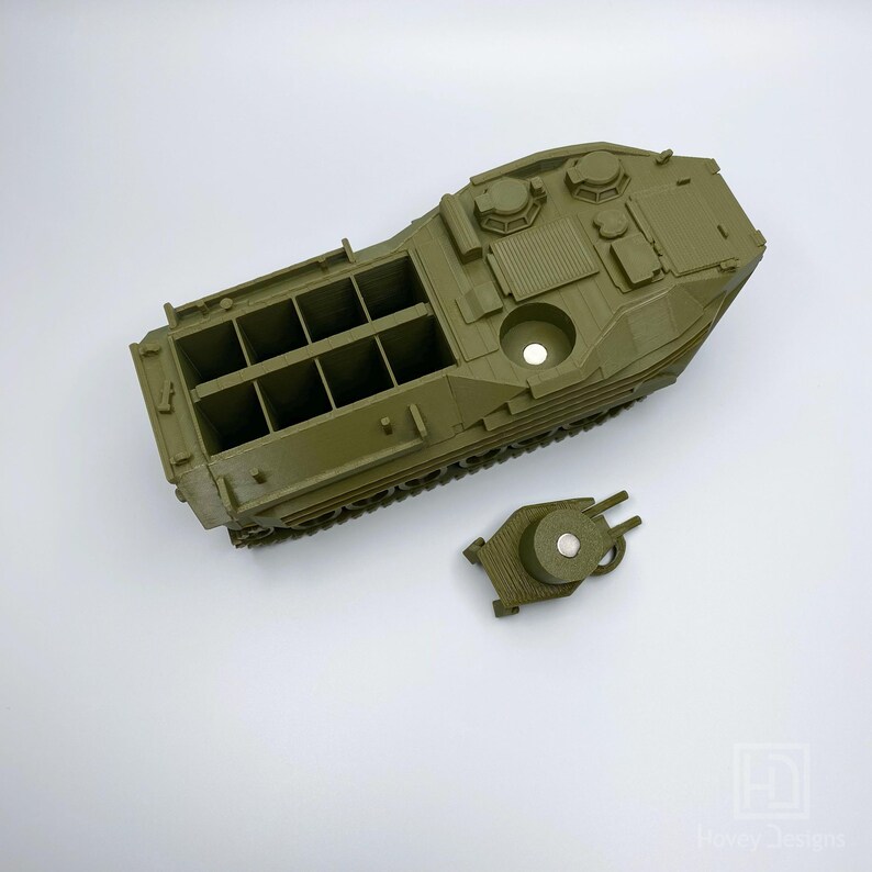 May include: A green plastic model of an amphibious armored vehicle with a removable turret. The vehicle has a detailed interior with multiple compartments and a track system.