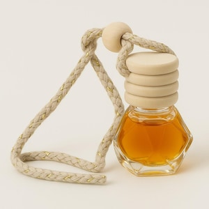 Peut inclure: Une bouteille en verre contenant un liquide doré, avec un bouchon en bois et une corde beige attachée. La bouteille est en forme de diamant et a une surface texturée.