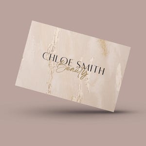 May include: A beige business card with a marble-like texture and gold glitter accents. The text "CHLOE SMITH Beauty" is printed in black and gold.