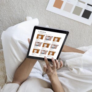 Puede incluir: Una pantalla de tableta que muestra un sitio web con una cuadr&iacute;cula de camisetas a la venta. El t&iacute;tulo del sitio web es "T-SHIRTS".