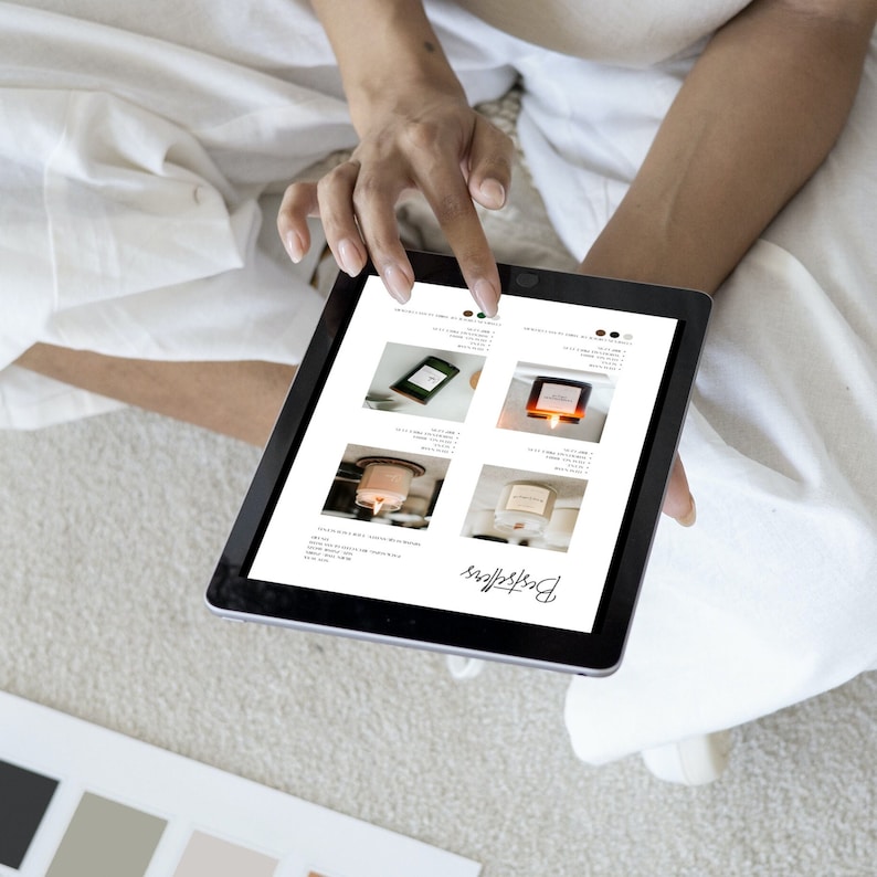 Puede incluir: Una persona usa una tableta que muestra una lista de productos. La pantalla muestra cuatro opciones de velas diferentes con varios envases y etiquetas. La palabra "Bestsellers" est&aacute; escrita en cursiva en la parte inferior de la pantalla. La persona est&aacute; sentada sobre una superficie blanca.