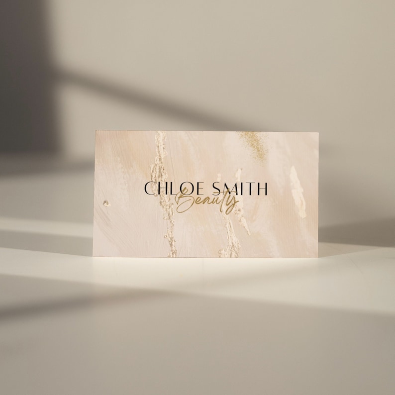 May include: A beige business card with a gold glitter background and the text "CHLOE SMITH Beauty" in black and gold lettering.