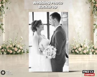 May include: Black and white wedding photo backdrop featuring a bride and groom. The backdrop has the text "Wedding Photo Backdrop" at the top. The couple is embracing, with the bride holding a bouquet. Floral arrangements frame the backdrop.