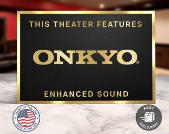 May include: A black rectangular sign with gold lettering and trim. The text reads "THIS THEATER FEATURES ONKYO ENHANCED SOUND." A small "Made in the USA" emblem and a "Fast Delivery" icon are visible.