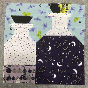 May include: A purple and white fabric block with a black and white bat pattern, a white fabric block with purple polka dots, and a light blue fabric block with a black bat pattern. The fabric blocks are arranged in a pattern to create a Halloween-themed design.