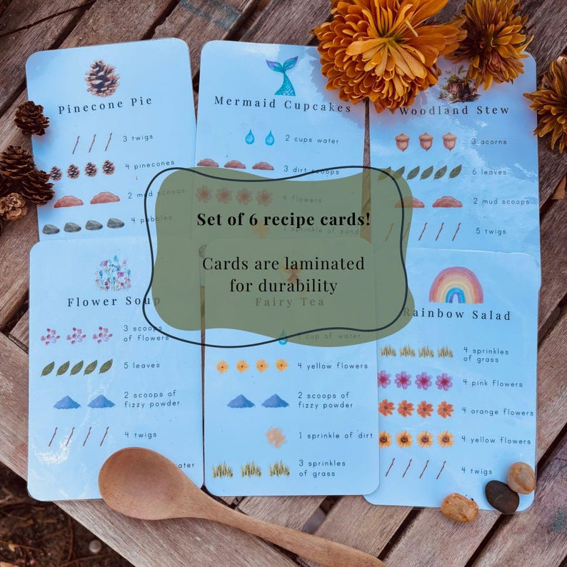 May include: A set of six laminated recipe cards for nature-themed play, featuring illustrations of pinecones, mermaid tails, acorns, flowers, and rainbows. Each card lists ingredients like twigs, leaves, and mud scoops with text labels for each item.