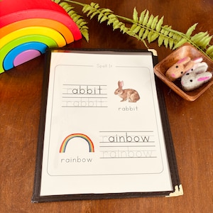 May include: A black and white printable worksheet with the words "Spell It" at the top. The worksheet has two sections, one with a picture of a rabbit and the other with a picture of a rainbow. The words "rabbit" and "rainbow" are written below each picture, with lines for tracing the letters.