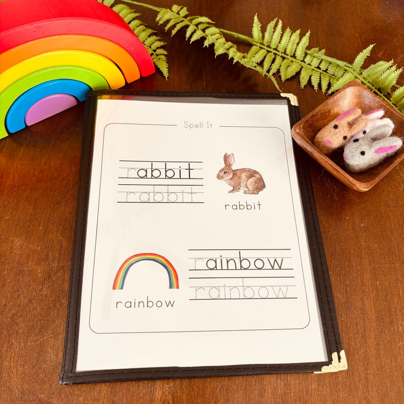 May include: A black and white printable worksheet with the words "Spell It" at the top. The worksheet has two sections, one with a picture of a rabbit and the other with a picture of a rainbow. The words "rabbit" and "rainbow" are written below each picture, with lines for tracing the letters.