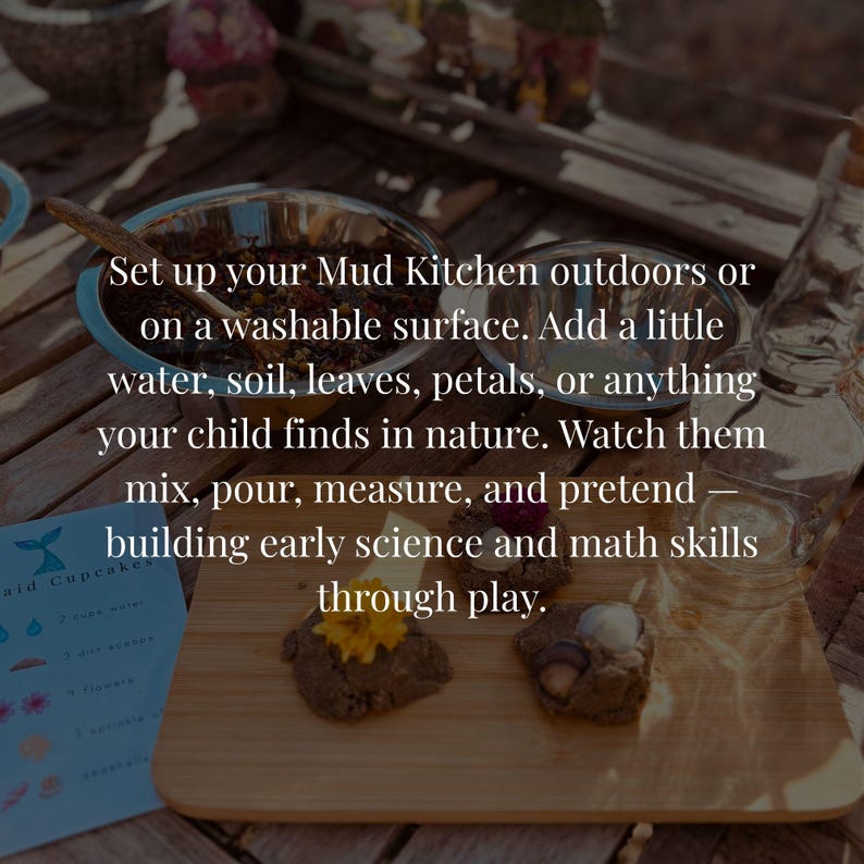 May include: A mud kitchen play set featuring two stainless steel bowls, a wooden cutting board with two mud cakes topped with yellow flowers and white stones, and a blue instruction card with the text Mermaid Cupcakes and ingredient icons.