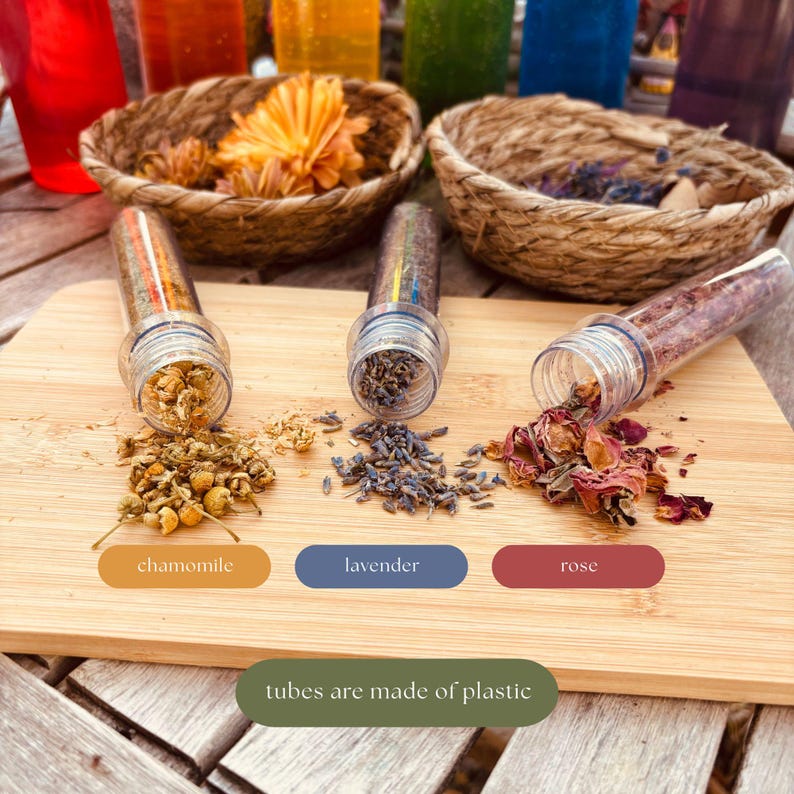 May include: Three clear plastic tubes containing dried chamomile flowers, lavender buds, and rose petals are arranged on a wooden board. Each tube is labeled with its contents: chamomile, lavender, and rose. The tubes are made of plastic.