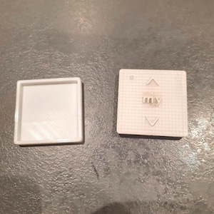 Può includere: Due pulsanti quadrati bianchi, uno con la parola "my" stampata e l'altro vuoto.