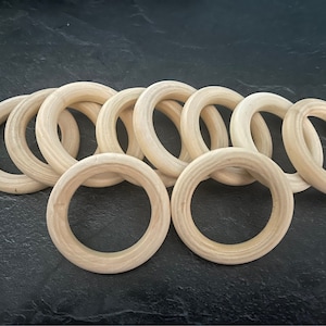 Puede incluir: Un conjunto de diez anillos de madera, todos del mismo tamaño y forma. Los anillos son de color marrón claro y tienen un acabado liso y pulido.