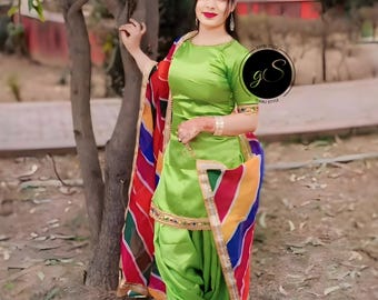 Peut inclure: Une femme portant un salwar kameez vert avec un dupatta coloré. Le dupatta a un motif rayé avec des rayures rouges, jaunes, bleues et vertes. Le kameez a un col rond et des manches courtes. Le salwar est un pantalon ample.