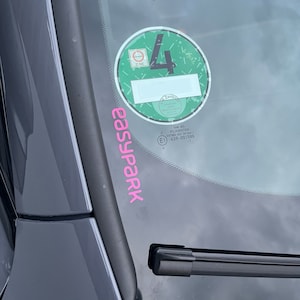 Könnte beinhalten: Ein grüner Umweltzonen-Aufkleber mit der Nummer 4 auf einer Windschutzscheibe. Der Aufkleber hat den Text "Umweltzone" und "Zentrum" darauf. Der Aufkleber hat auch den Text "VW AG PILKINGTON 00151 43H-001586".