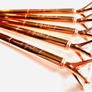 Puede incluir: Cinco bol&iacute;grafos de oro rosa con tapas transparentes en forma de diamante. Cada bol&iacute;grafo est&aacute; grabado con la palabra "Grateful" y un s&iacute;mbolo de coraz&oacute;n.