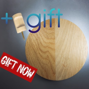 Può includere: Un ripiano a muro rotondo in legno con finitura in legno naturale. Il ripiano è fissato alla parete con un piccolo gancio in legno. Il testo "gift" è scritto in lettere blu sopra il ripiano. Il testo "GIFT NOW" è scritto in lettere rosse sotto il ripiano.