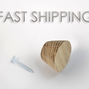 Puede incluir: Un pomo de madera con un diseño redondeado en forma de cono. El pomo es de color marrón claro con un patrón de veta de madera. Se incluye un tornillo plateado.