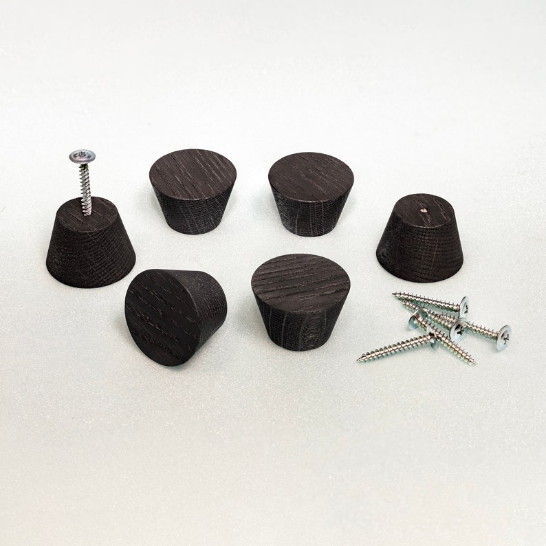 May include: A set of six dark brown, tapered wooden knobs with a visible wood grain texture. Each knob has a flat circular top and a wider base. One knob is attached to a metal screw, and four additional metal screws are included separately.