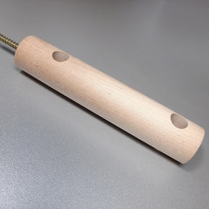 May include: A wooden dowel with two holes drilled through it. The dowel has a screw at one end.