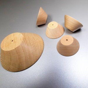 May include: Five wooden bowls of varying sizes, all with a natural wood finish and a smooth, rounded shape. The bowls are arranged on a light gray surface.