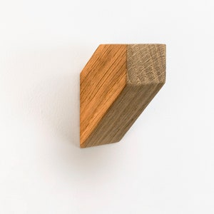May include: A wooden wall hook with a geometric shape. The hook is made of light brown wood and has a natural finish.