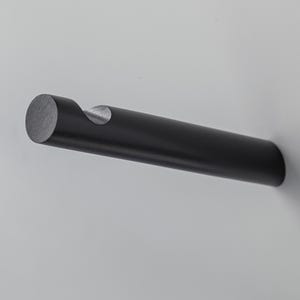 May include: A black, cylindrical bottle opener with a circular end and a curved notch for removing corks. The opener is mounted on a white surface, showcasing its sleek, minimalist design. The opener is made of metal.