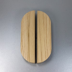 May include: Two wooden door pulls with a rounded top and a smooth, natural wood finish.