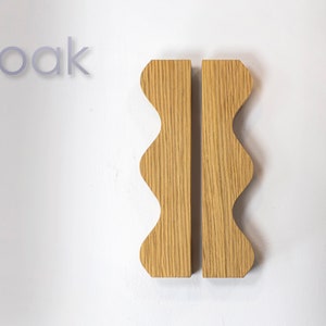 Könnte beinhalten: Zwei Holzgriffe mit einer gewellten Kante aus Eichenholz.