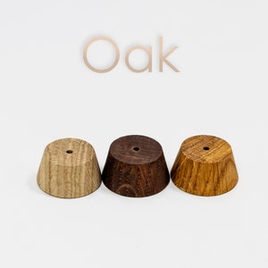 May include: Three wooden bases in different shades of brown, labeled "Oak". The bases are round and have a slight cone shape.