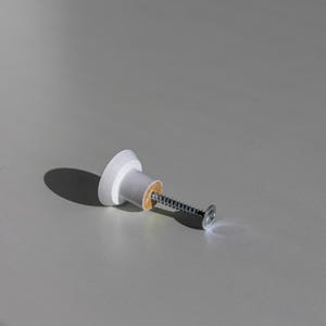 May include: A white and gray cabinet knob with a screw. The knob has a circular head and a cylindrical base. The screw is silver and has a flat head. The knob is likely made of wood and plastic.