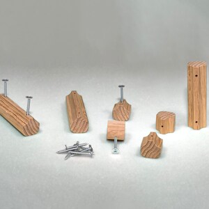 May include: A set of eight wooden knobs and pulls in various shapes and sizes. The knobs and pulls are made of light brown wood with a natural grain pattern. The set includes screws for installation.