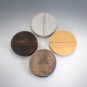 Puede incluir: Cuatro tiradores de cajón redondos de madera en diferentes manchas de madera: blanco, marrón, marrón claro y marrón oscuro. Cada tirador está dividido en dos, creando un elemento de diseño único.