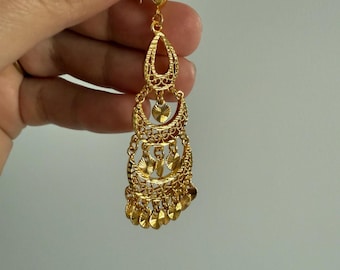 May include: A gold-tone dangle earring featuring a teardrop-shaped top section, a circular middle link with a small heart charm, and a tiered bottom section composed of multiple crescent-shaped filigree elements and small circular discs.