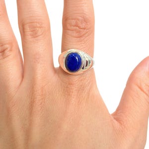 May include: A silver ring with a blue oval gemstone set in a bezel setting.