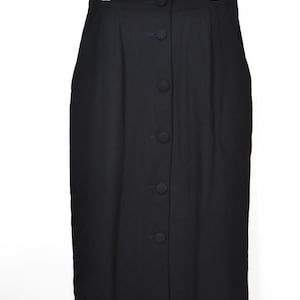 Puede incluir: Una falda negra con botones colgada de una percha. La falda es de color negro liso y parece estar hecha de una tela suave. Los botones recorren la parte delantera de la falda. La falda es de largo midi.