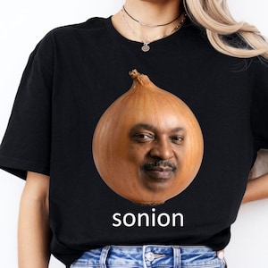 May include: Black t-shirt featuring a humorous graphic of an onion with a face, and the word "sonion" in white text below. The onion has a brown exterior and a man's face. The shirt is made of a soft material.