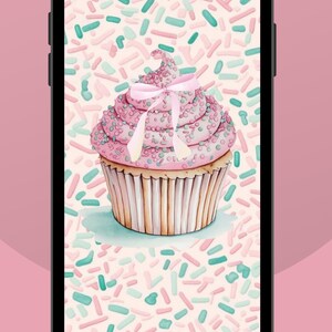 May include: A pink cupcake with white frosting and pink sprinkles, topped with a pink ribbon bow. The cupcake is on a white background with pink and green sprinkles.